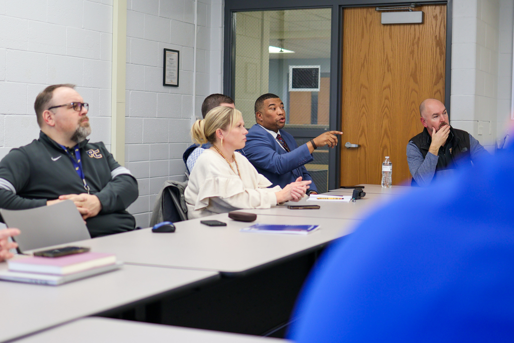 a man speaking at a table in a conference room