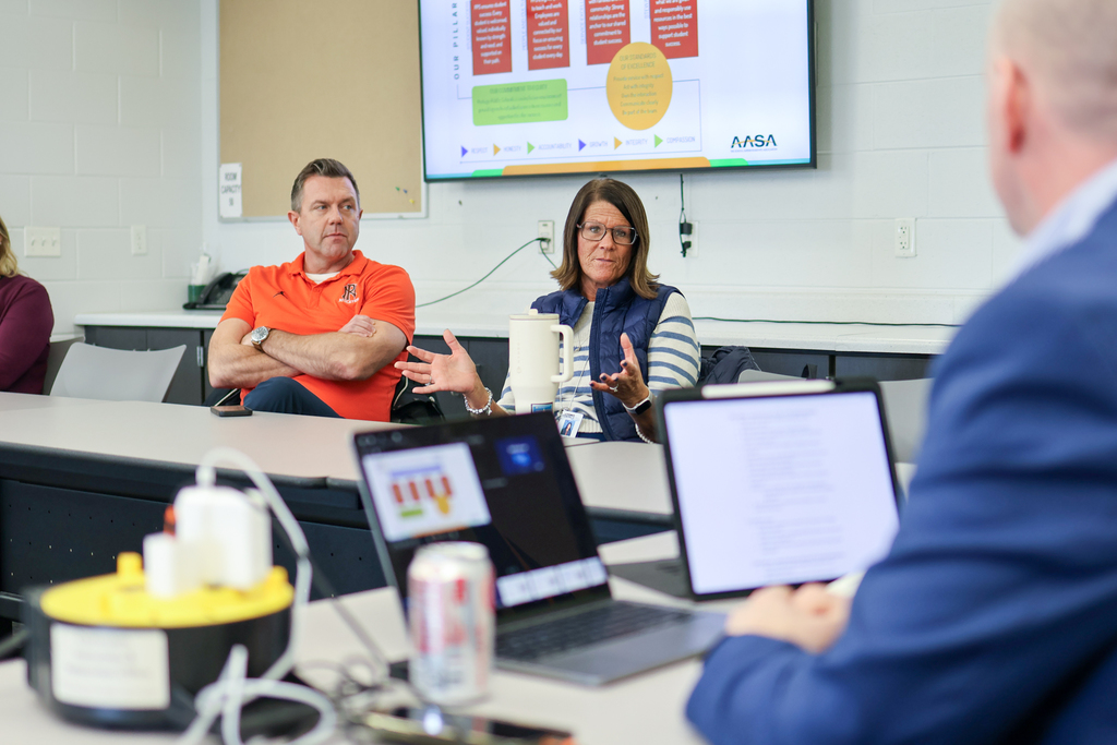 a woman speaking at a table in a conference room