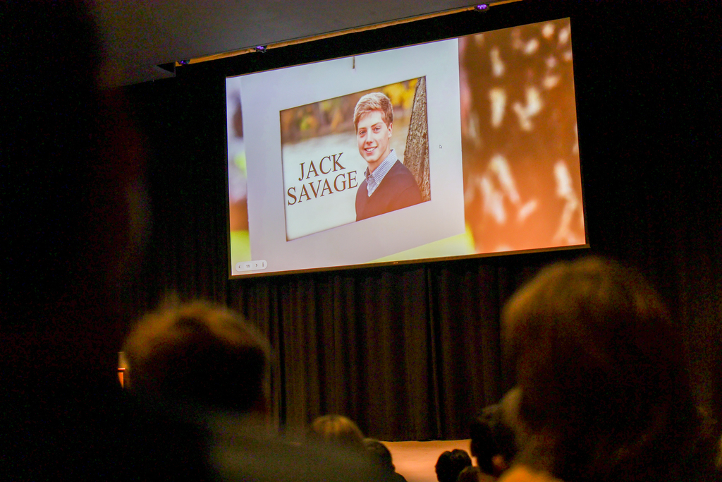 a screen with a photo of Jack Savage is displayed in the auditorium