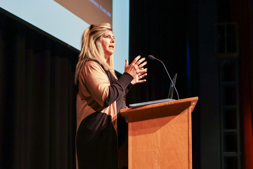 a woman speaking at a podium in an auditorium