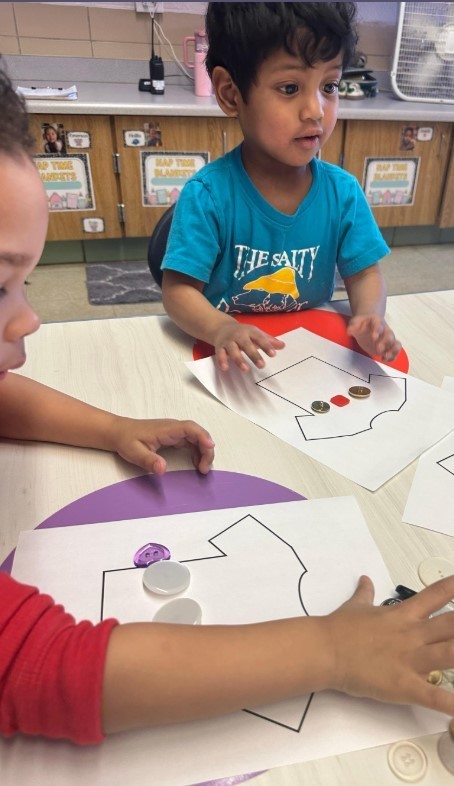 A little boy putting buttons on a shirt.