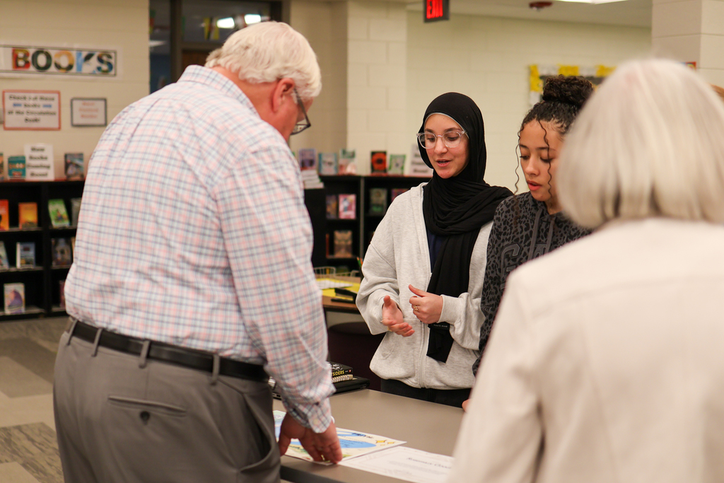 two girls talking to two adults in a school library