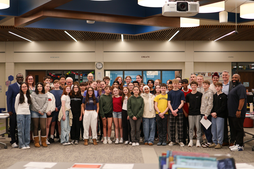a large group of students and adults pose for a photo in a library