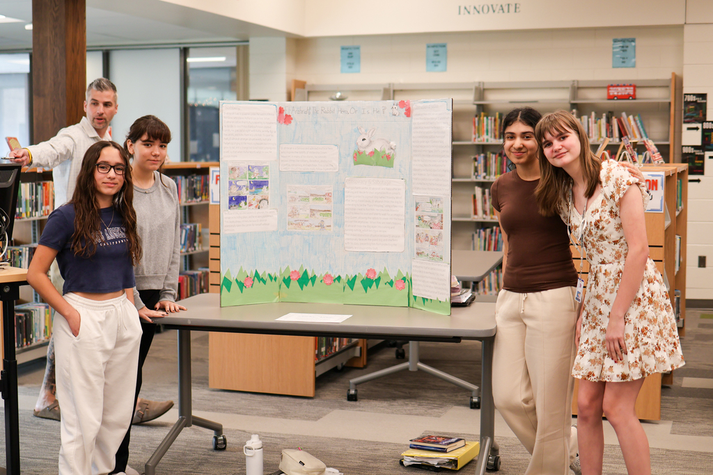 four girls pose for a photo with their posterboard project