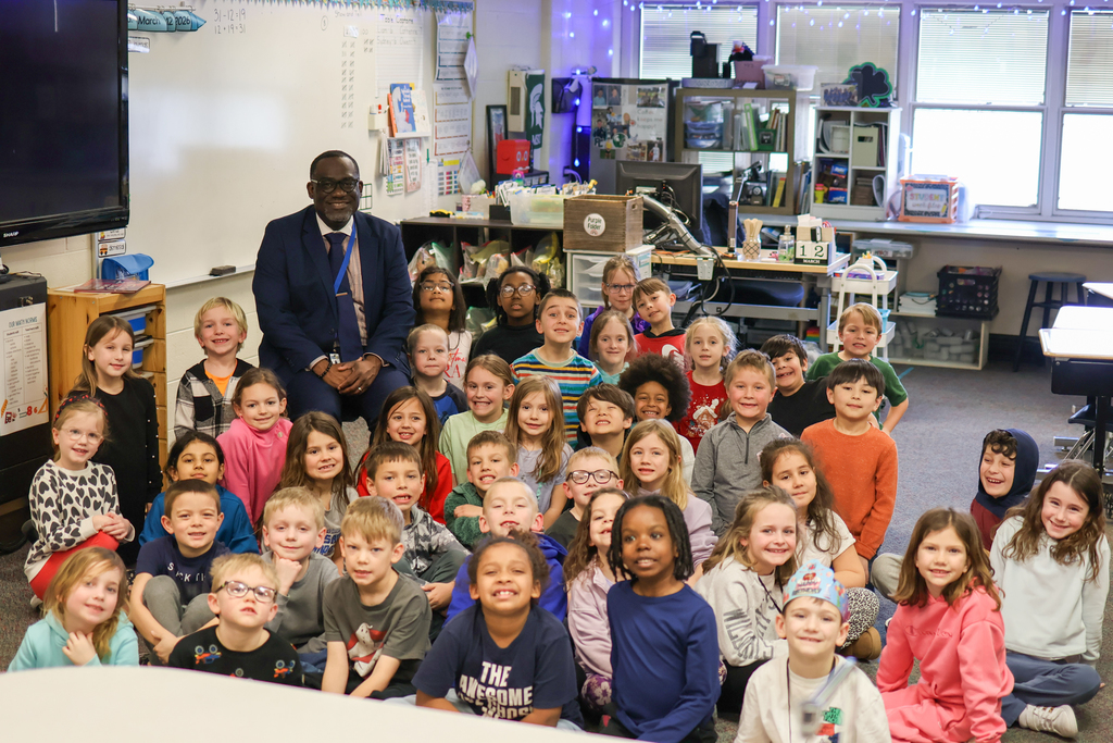 a man poses for a photo with a large group of students