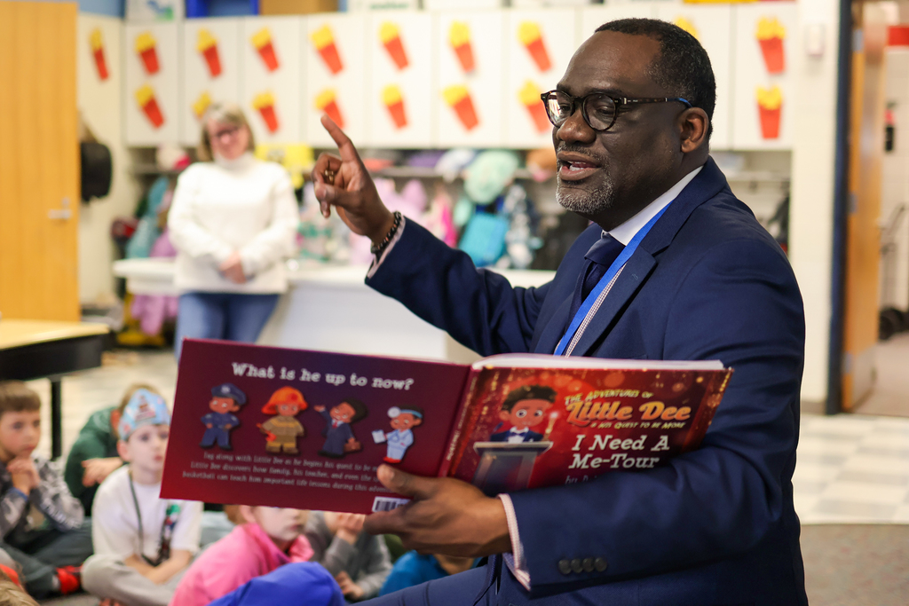 a man reading a book to students in a classroom