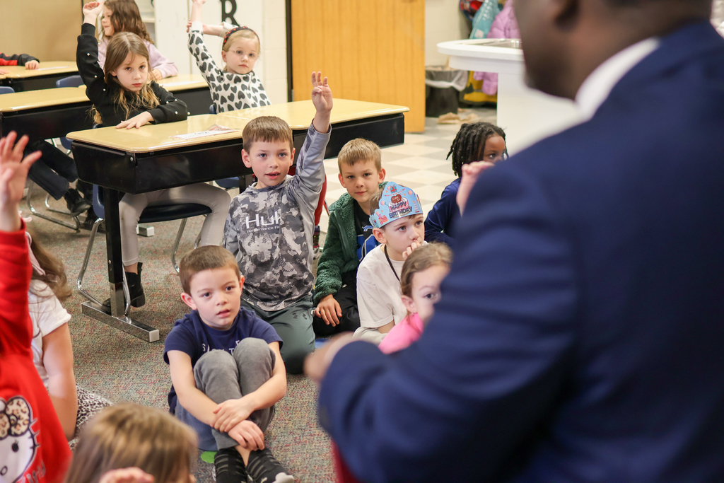 students raise their hands in a classroom