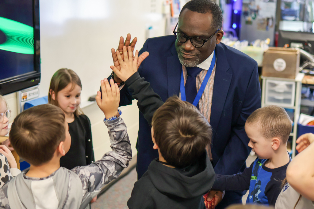 a man high fives students in a classroom