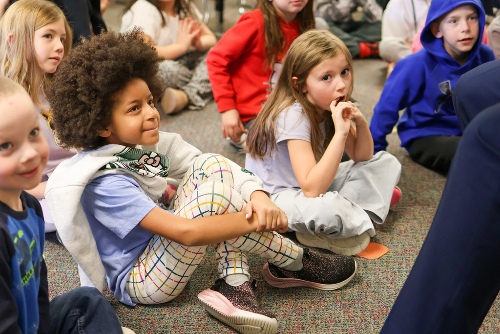 a girl sitting on the floor smiles up at a man