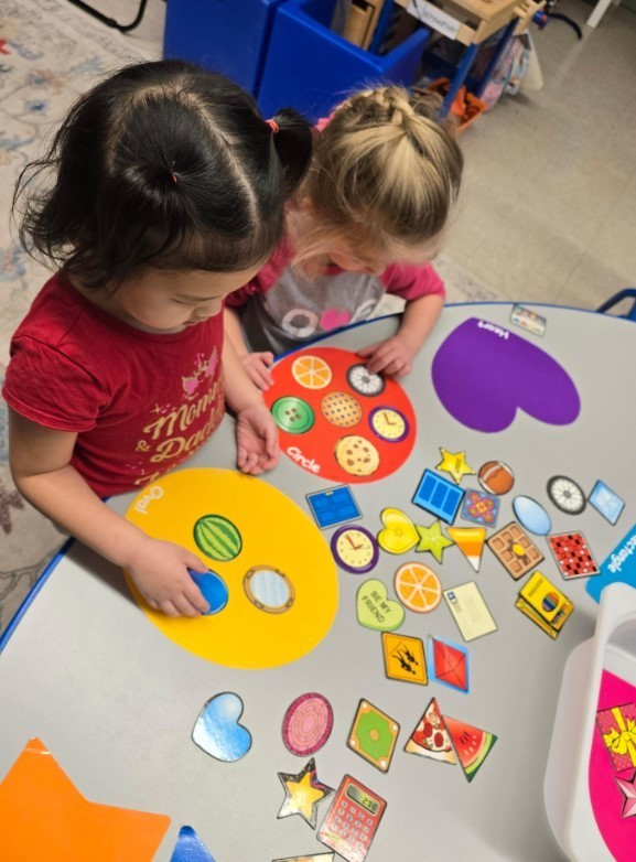 Two female students working on a matching puzzle together.