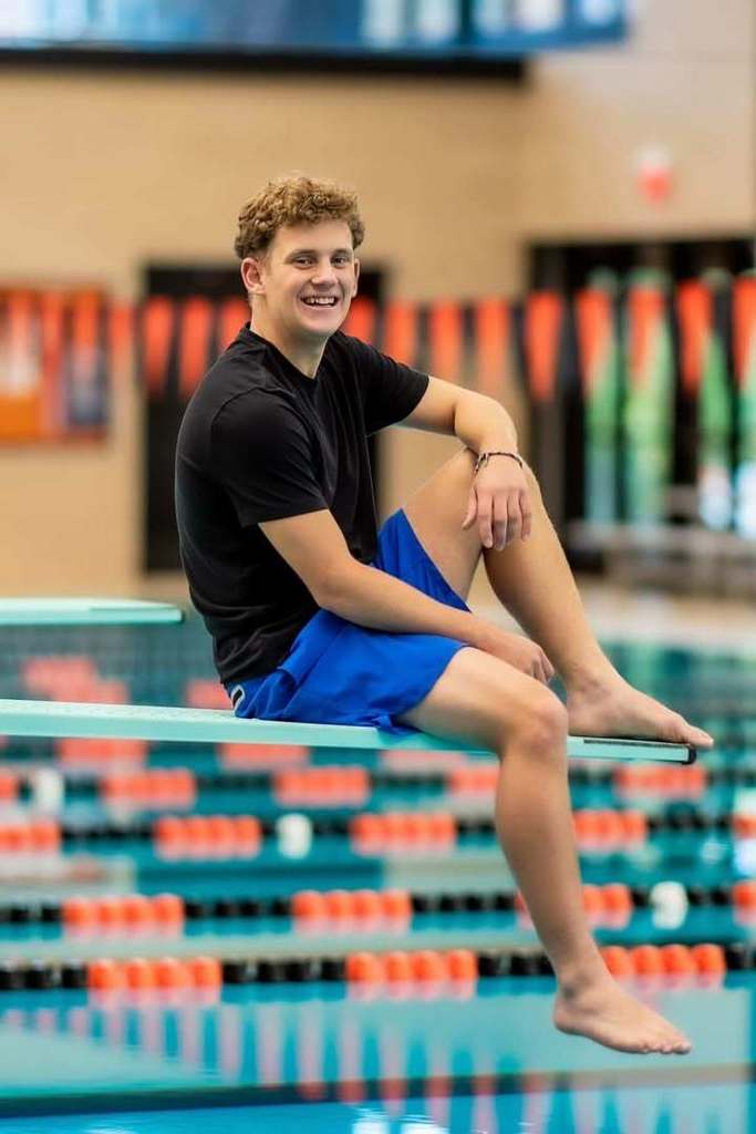 a photo of a boy sitting on a pool diving board.