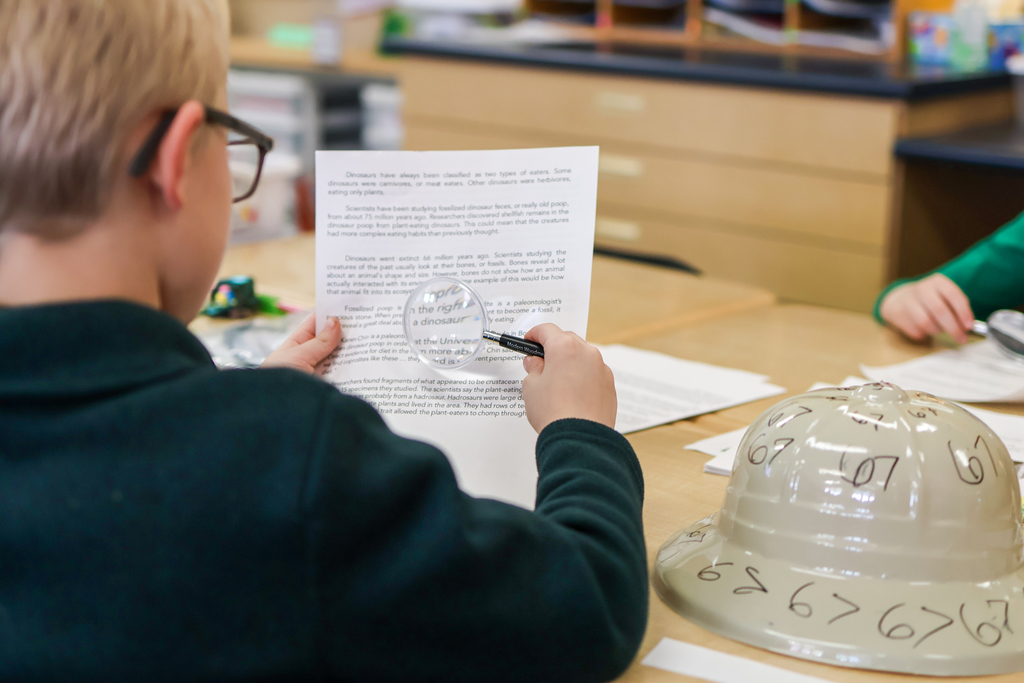 a student using a magnifying glass to look at a paper