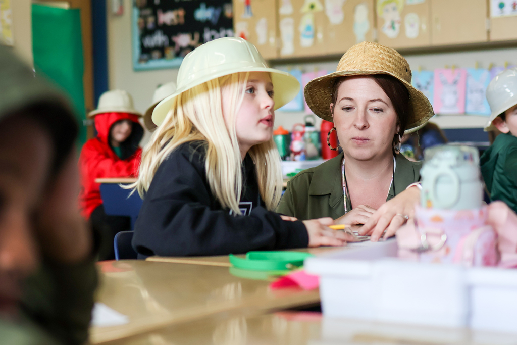 a teacher and student sitting at a desk in a classroom