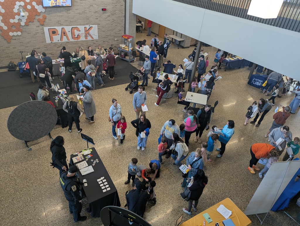 Wide view of registration event with people at various information tables