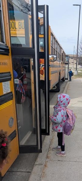 A little girl waiting to get on the bus.