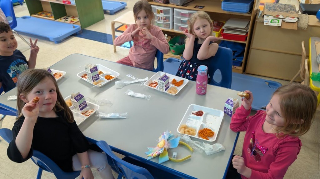 Students eating lunch together at a table in their classroom.