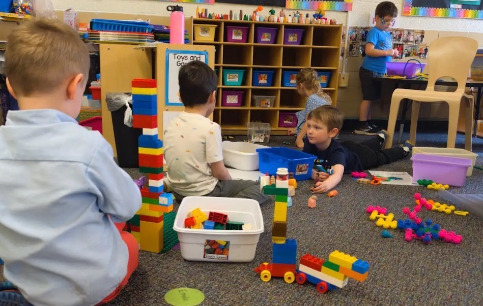 Four boys playing with legos and stacking them together.