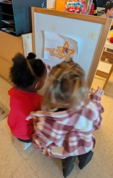 Two female three year olds looking at a paining together
