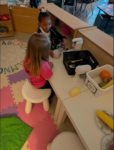 Two female students playing together in the kitchen area. 