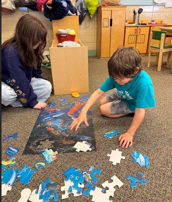 A female teenager playing with a puzzel with a male student.