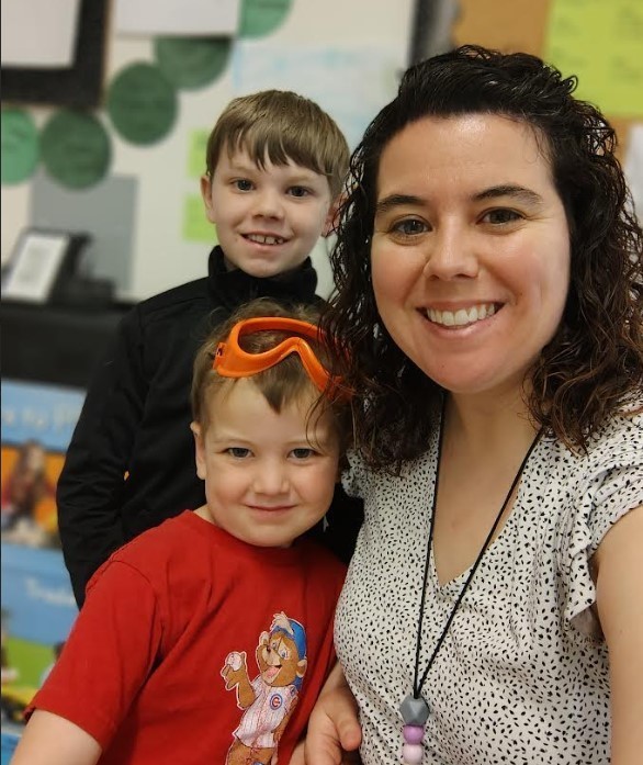A teacher and her two male children smiling in a picture. 