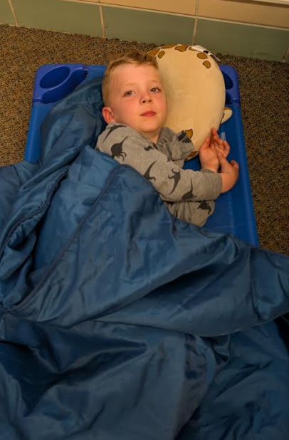 Student resting on a blue cot.