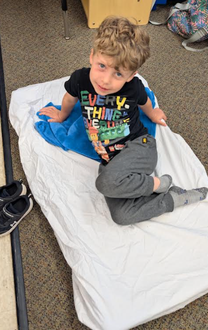 A male student resting on his cot and smiling. 