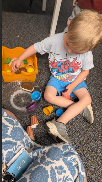 A little boy sitting on the floor playing with pretend ice cream cones.