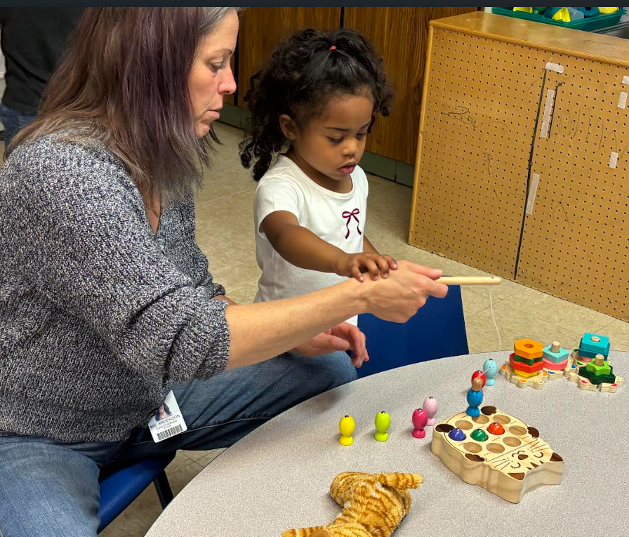 Tecaher and student playing with pegs and standing.