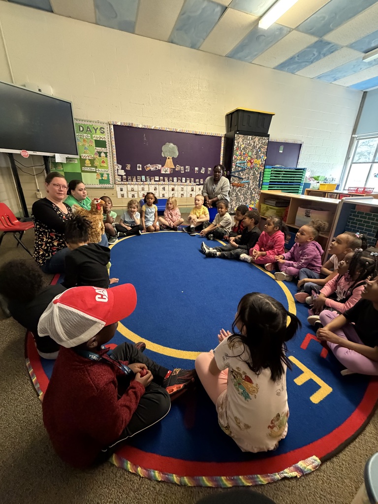 A group of students sitting at the rug together. 