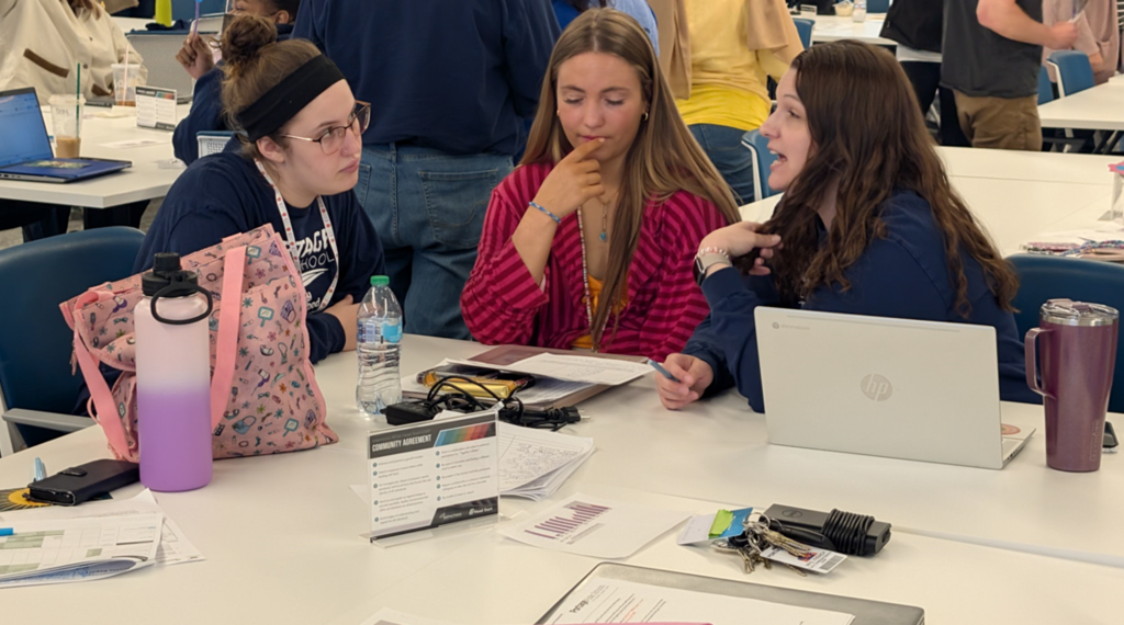Three teachers sitting together at a large table. 