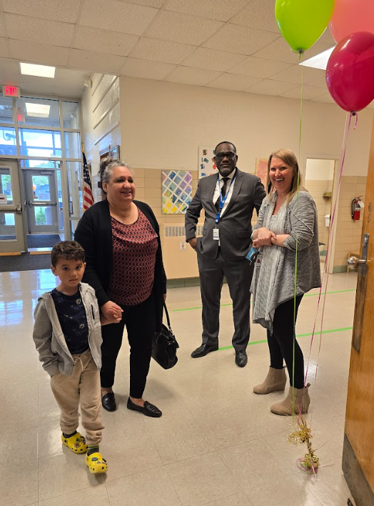 Three adults and a child standing in the hallway together. 