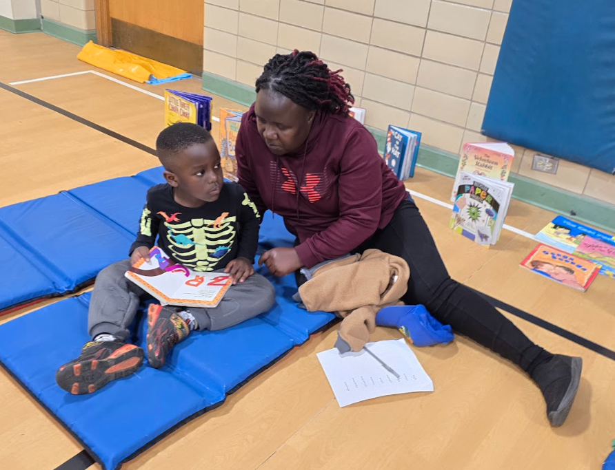 A boy and his Mom sitting together and reading a book.