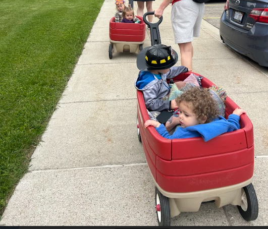 A group of toddlers being pulled on a wagon. 