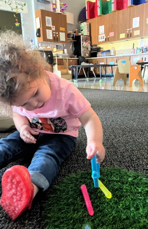 A femal student using tweezers to pick up pretend worms.