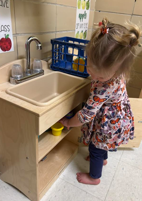 A toddler girl playing in the kitchen. 