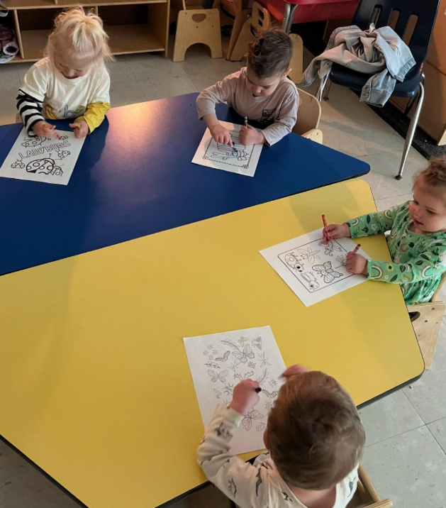 A group of toddlers coloring a bug worksheet.