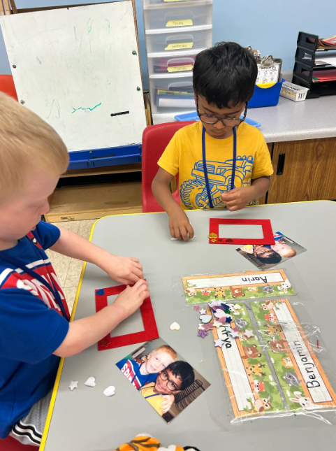 Two preschool boys creating a picture frame together.