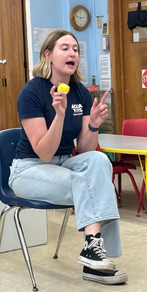 A swim teaching holding a yellow duck to talk about swimming safety. 