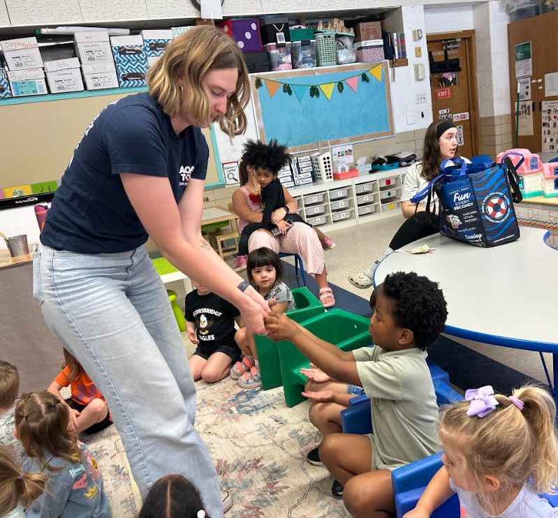 The teacher helping the student feel an item.