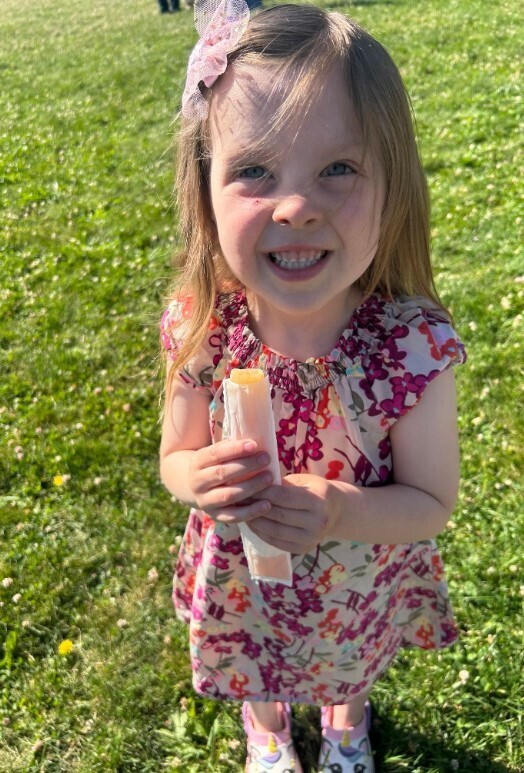 A little girl student holding a popscicle and smiling. 