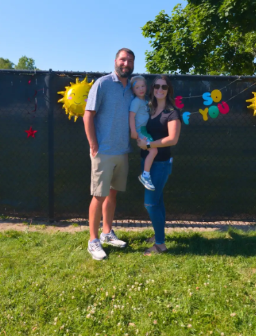 Two parents and their three year old son smiling for a picture. 