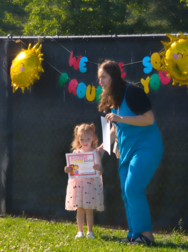 A teacher and a child holding a certificate.