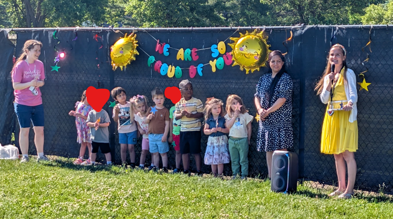 Three Year Old  Preschool  Class standing together against a fence outside. 