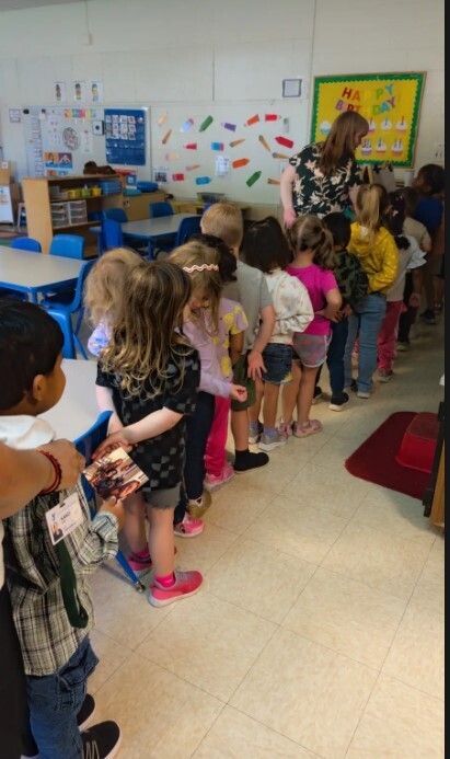 Four year old students lining up in the classroom getting ready to head outside together.