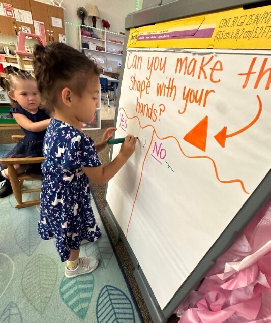 A female student writting on a large chartboard.