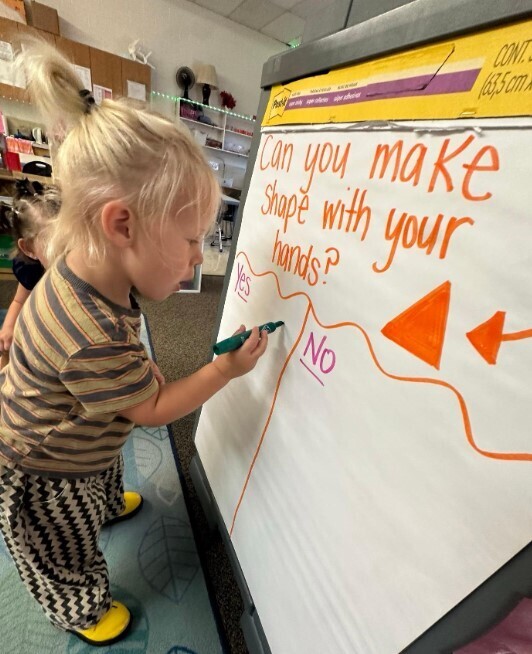 A male student writting on a large charboard in the classroom.