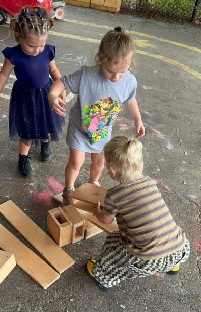 Students playing with large blocks outside on the blacktop.