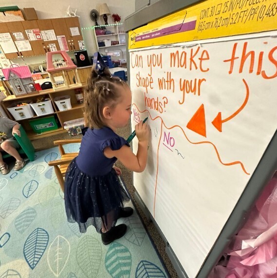 A female student writting on a large chartboard.