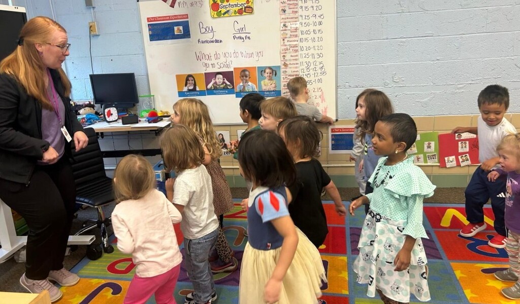 Students all dancing together on the carpet in the classroom.
